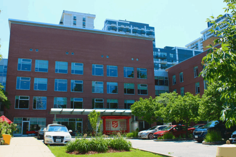 Exterior view of the Isabel and Arthur Meighen Manor building, a multi-story brick residence with the Salvation Army entrance and landscaped grounds.